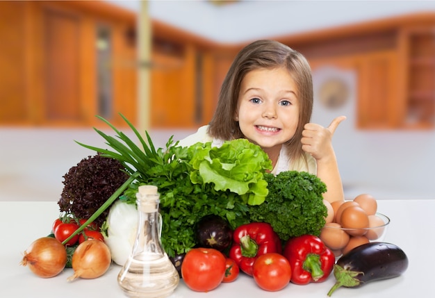 Niña linda con verduras en la cocina