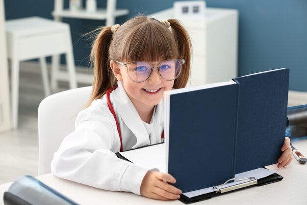 Niña linda vestida como médico jugando en casa