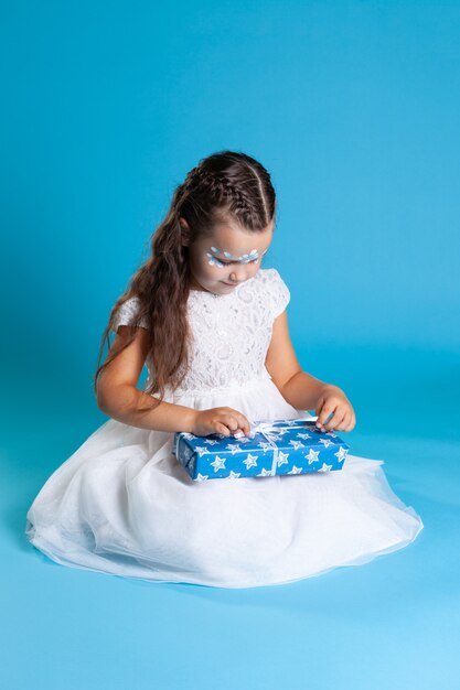 Niña linda con un vestido blanco con un regalo