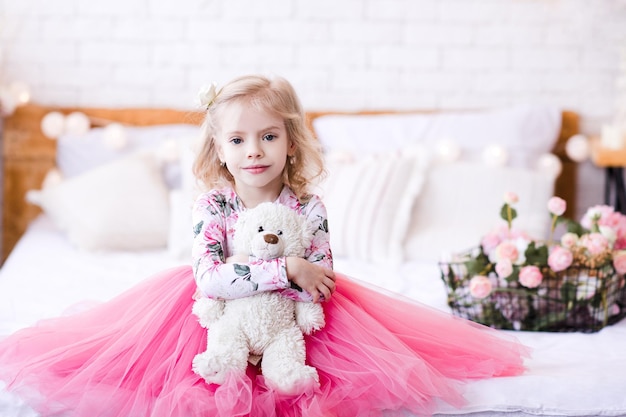 Niña linda con vestido de princesa con oso de peluche