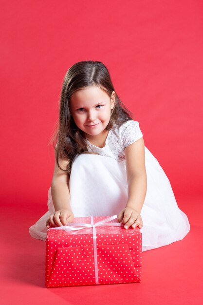 Niña linda en un vestido con un regalo de Navidad