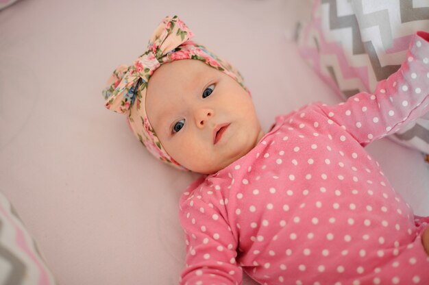 Niña linda en el vestido rosa acostada en su acogedora cama