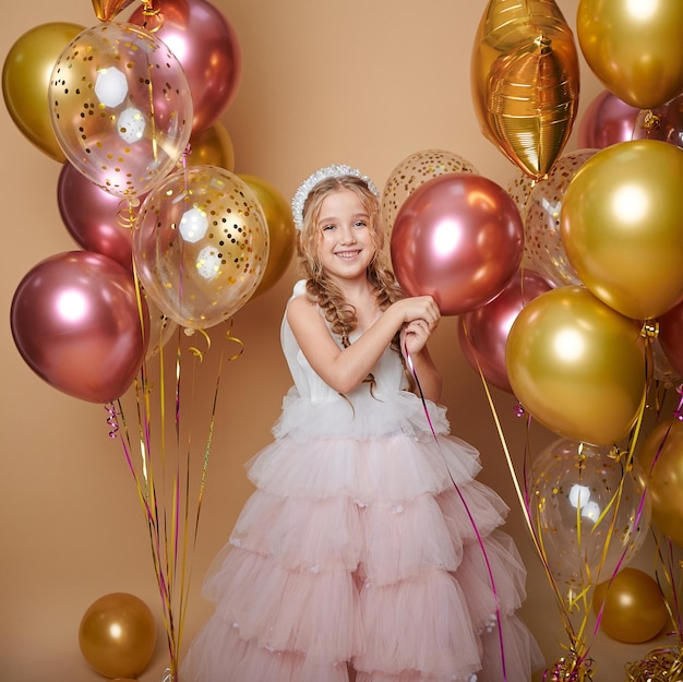 Niña linda en vestido rosa con globos grandes