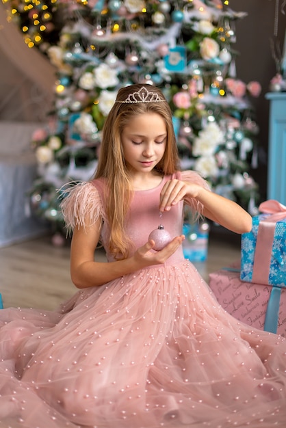 Niña linda en un vestido rosa en Navidad