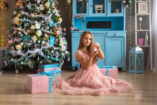 Niña linda en un vestido rosa en Navidad