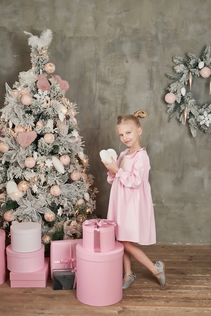 Niña linda en vestido rosa con regalos