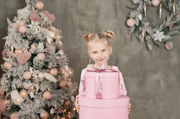 Niña linda en vestido rosa con regalos