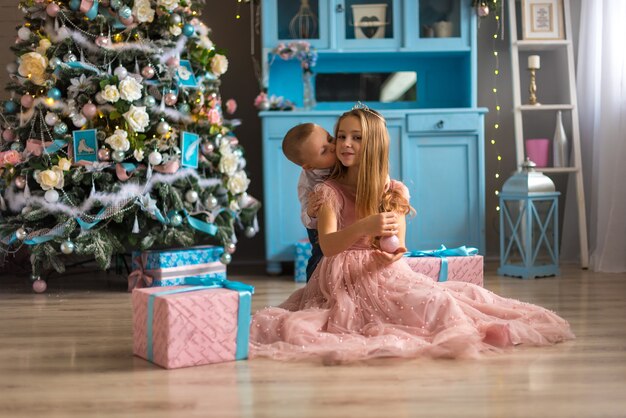 Niña linda en un vestido rosa con su hermano en Navidad