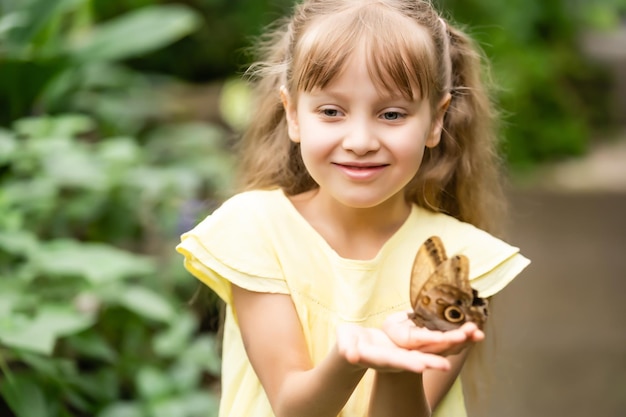 Niña linda con vida hermosa mariposa en su mano