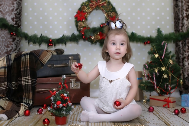 Niña linda se viste de árbol de Navidad en el piso de la habitación