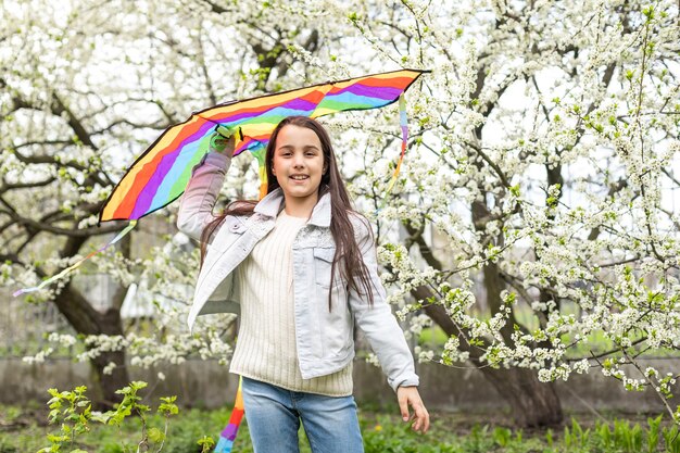 niña linda volando una cometa arcoiris.