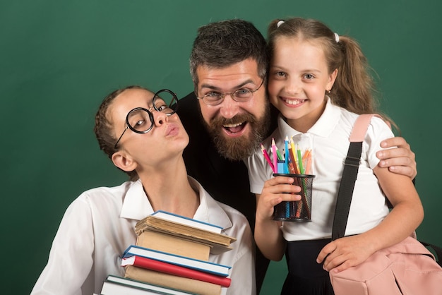 Una niña lleva una gran pila de libros, maestros y estudiantes con una gran colección de libros en las manos.