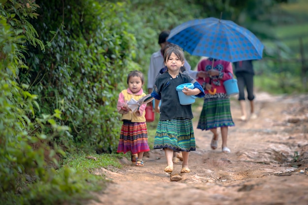 Una niña lleva paquetes de arroz en un camino rural cerca de su casa. Para ir a ver a sus padres mientras cultivaba arroz durante el día en Mu Cang Chai, Yenbai, Vietnam