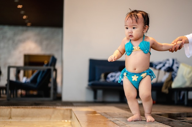 Niña lleva puesto de traje de baño cerca de la piscina