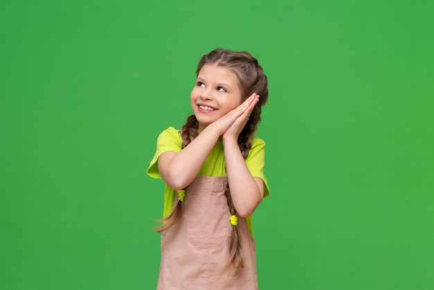 Foto la niña se llevó las manos a la mejilla y miró hacia otro lado sonriendo.