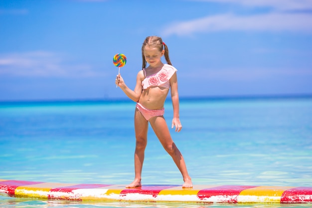 Niña con lollipop divertirse en tabla de surf en el mar