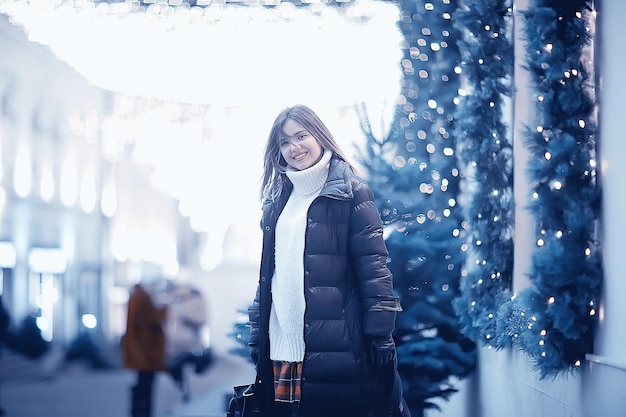 niña luces de navidad ciudad decorada por la noche, una joven modelo en el fondo de decoraciones urbanas y guirnaldas, luces nocturnas de la ciudad