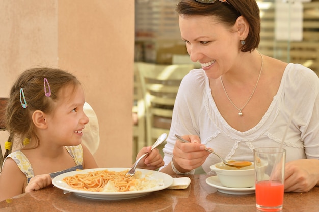 Niña con madre comiendo en la mesa