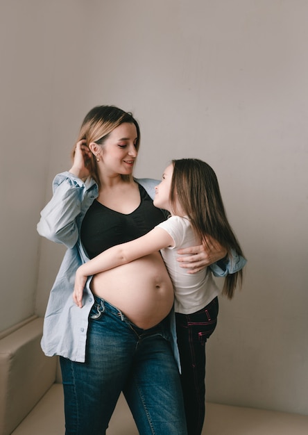 Niña y madre embarazada cariñosa hermanita junto al vientre de la madre. familia feliz