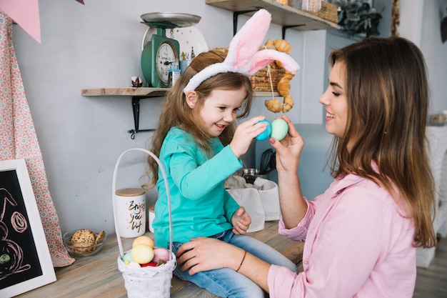 Niña y madre jugando con huevos de pascua