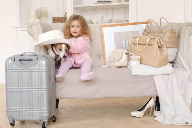 Una niña con maletas y un perro en el interior.