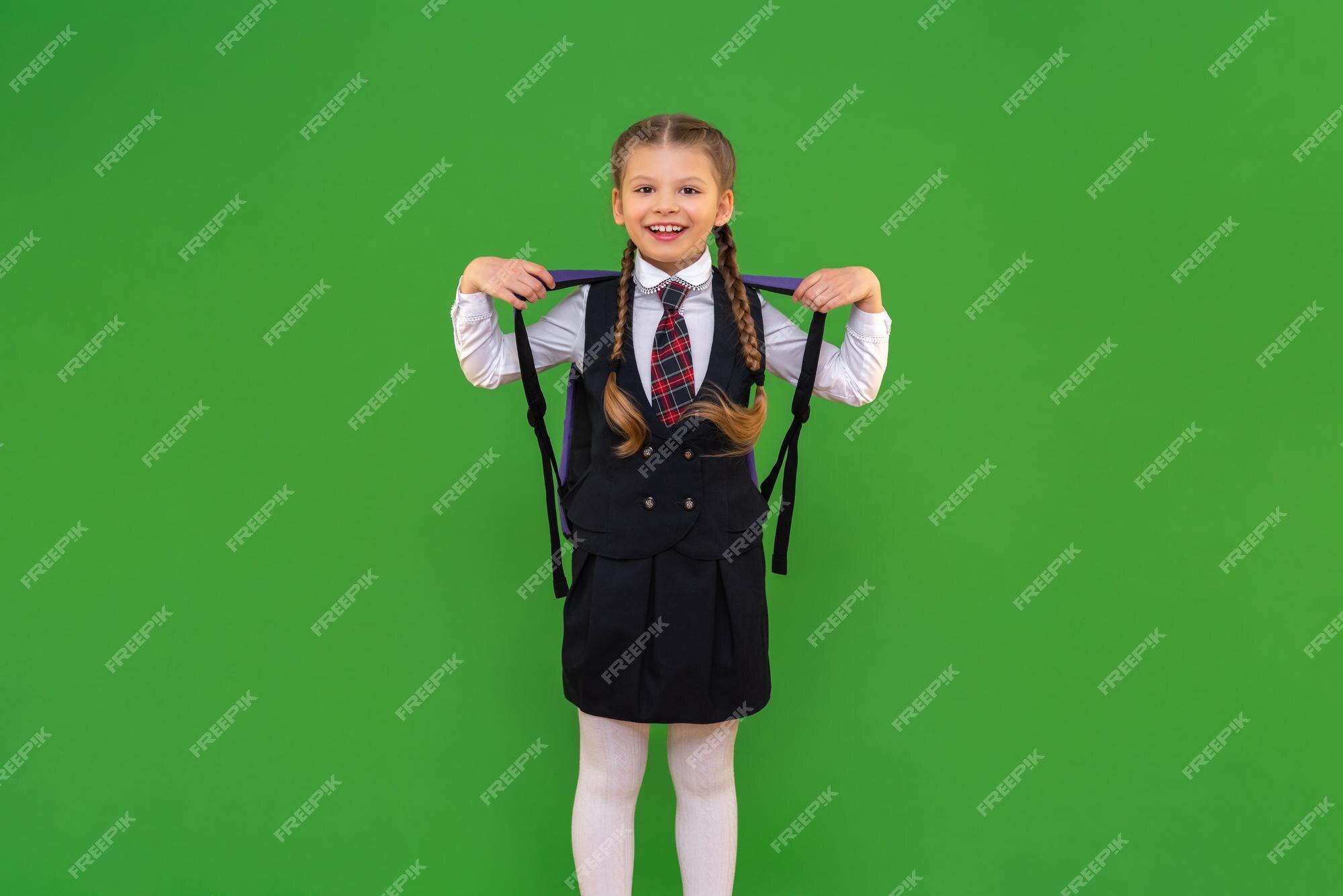 A niña con un maletín en un uniforme escolar realmente le gusta la escuela un estudiante sonriente se está divirtiendo con un fondo verde aislado estudiando material escolar obteniendo una