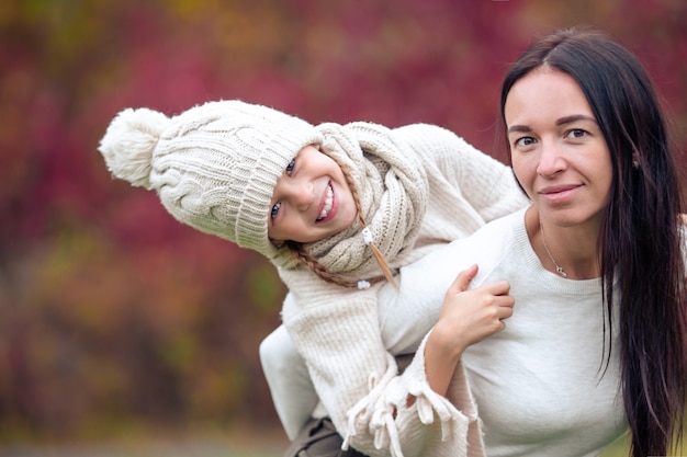 Niña con mamá al aire libre en el parque en día de otoño