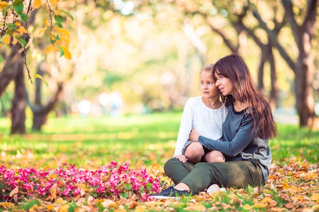 Niña con mamá al aire libre en el parque en día de otoño