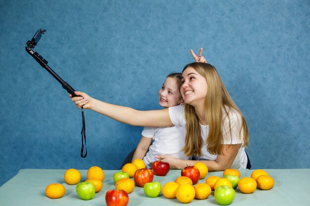 Niña con mamá en camisetas blancas tomar un selfie en el teléfono y jugar