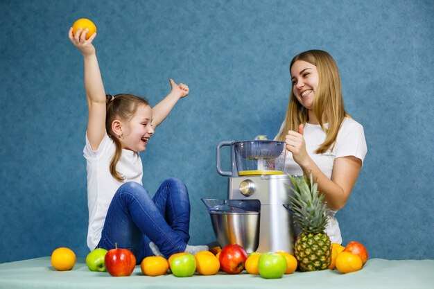 Niña con mamá juega con frutas y sonriendo. Vitaminas y nutrición saludable para niños.