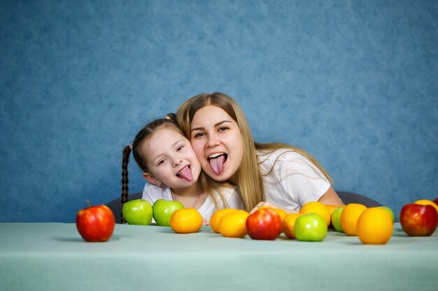 La niña y la mamá juegan con frutas y bromean. Llevan camisetas