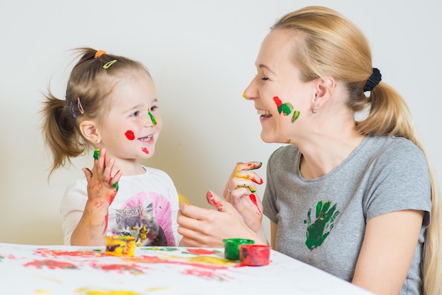 Niña con mamá jugando y jugando con pinturas de colores