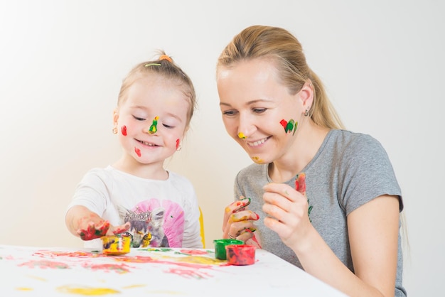 Niña con mamá jugando y jugando con pinturas de colores