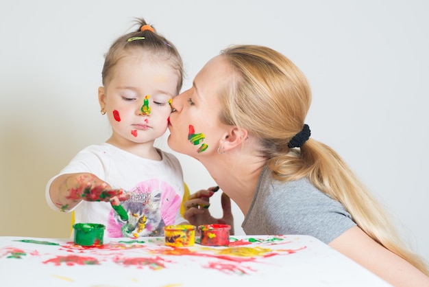 Niña con mamá jugando y jugando con pinturas de colores