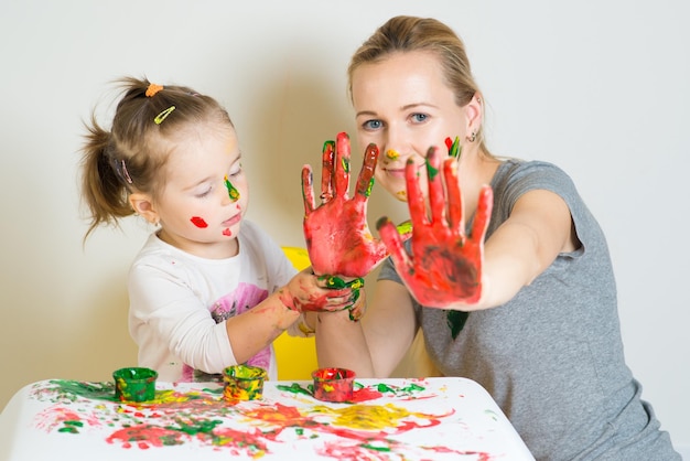 Niña con mamá jugando y jugando con pinturas de colores