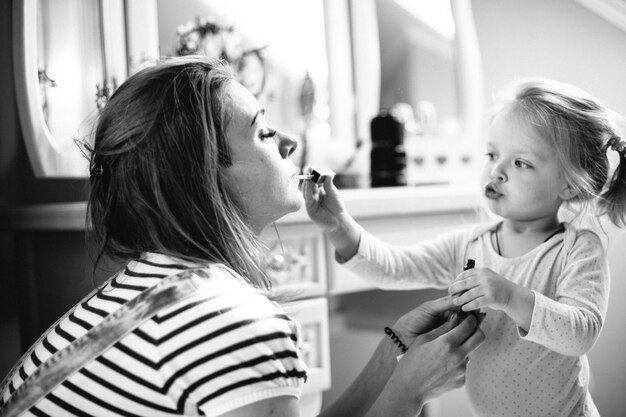 Niña y mamá pintando maquillaje cerca del tocador