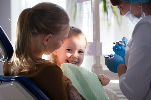 Niña con mamá en la silla del dentista - el niño está sonriendo, de cerca