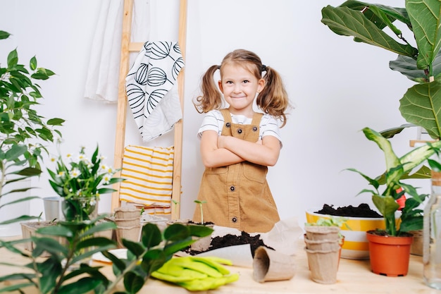 Niña mandona de pie junto a una mesa con tierra y plantas