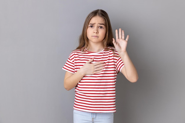 Niña con la mano en el corazón jurando decir la verdad, el honor y la conciencia