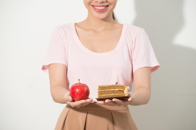 La niña en una mano tiene una manzana, en la otra un pastel.