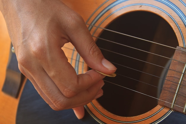 Foto niña mano tocando la guitarra acústica