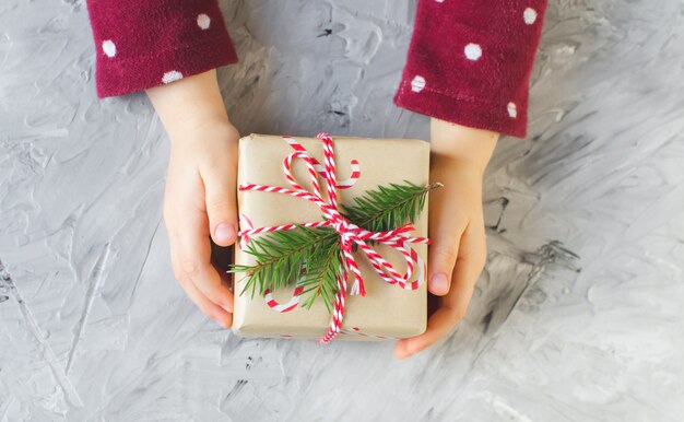 Niña de las manos con caja de regalo de Navidad