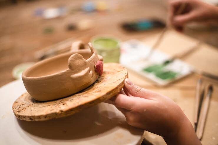 Foto niña manos estudio de cerámica y taza de pintura en el taller para hacer una taza creativa en forma de rana pintor producto de cerámica y proceso de pincel patrón artístico o producción en pequeñas empresas