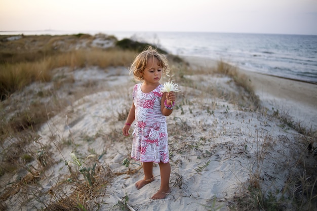 Niña en el mar mirando la flor