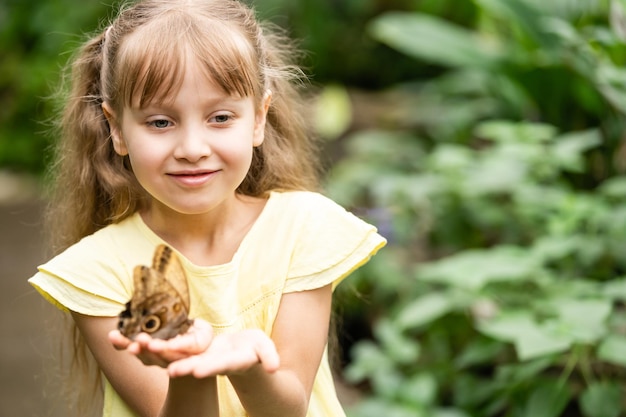 Niña con mariposa en la mano.