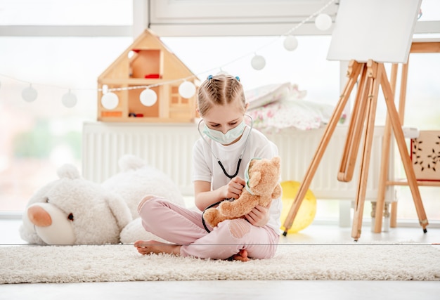 Niña en máscara jugando al doctor