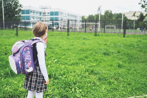 Niña con una máscara protectora en la escuela