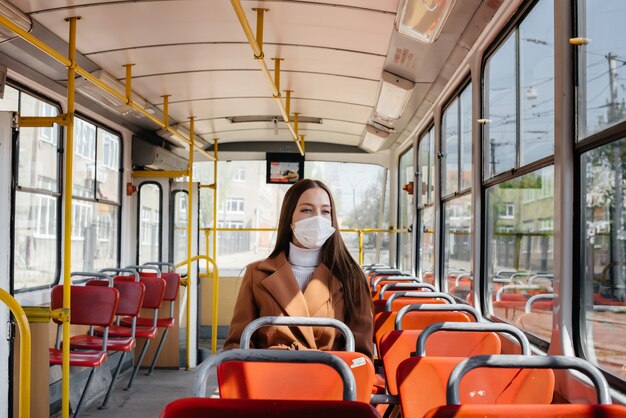 Una niña con una máscara usa el transporte público sola, durante una pandemia. Protección y prevención covid 19.