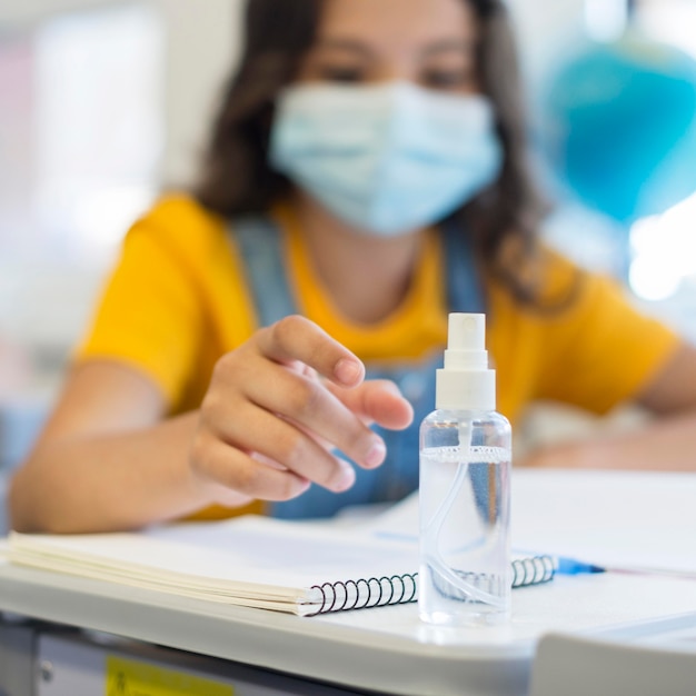 Foto niña con mascarilla y desinfectante para manos