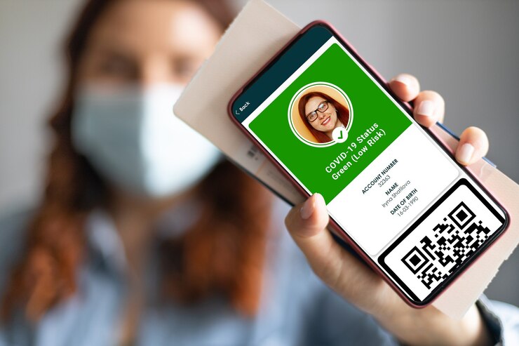 Foto niña con una mascarilla que sostiene un pasaporte, un boleto y un teléfono inteligente con una aplicación de pasaporte de salud digital para viajar durante la pandemia del covid-19.
